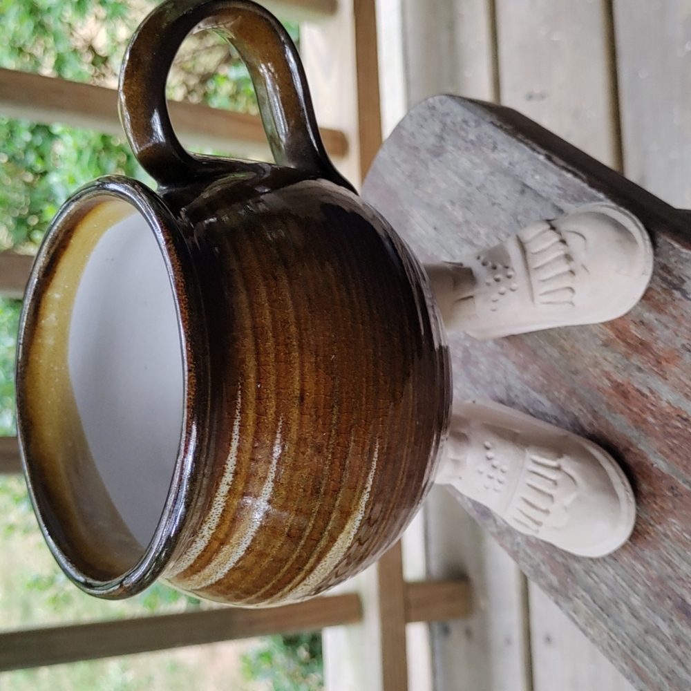 Brown glazed coffee mug with men's shoes